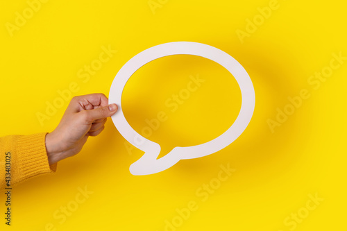 Dialogue bubble in hand over yellow background photo