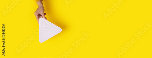 hand holding media player button icon over trendy yellow background, panoramic mockup