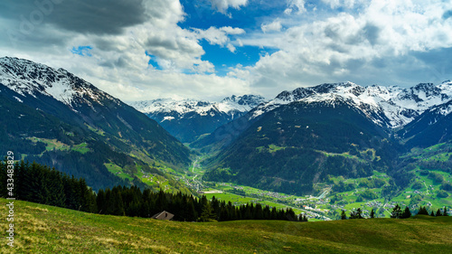 Blick von Bartholomäberg durch das Montafon zu den schneebedeckten Bergen des Rhätikon und Verwall im Vorarlberg. blumenübersäte Alpwiesen im Frühling und eine Föhnstimmung, blue cloudy sky with storm