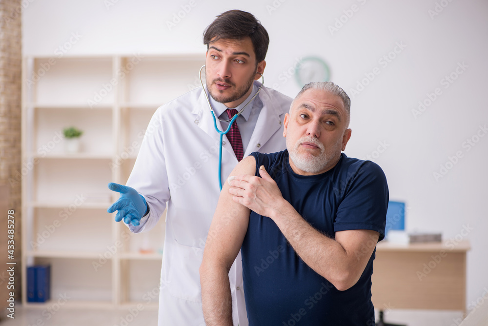 Obraz premium Old male patient visiting young male doctor in vaccination conce