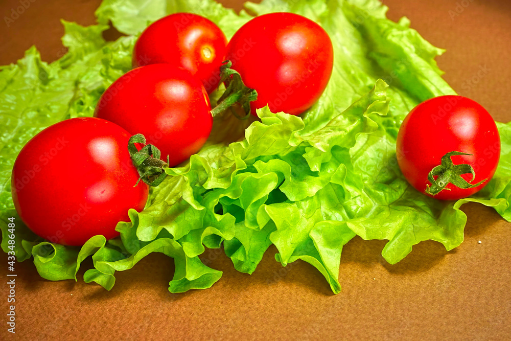 Red cherry tomatoes lie on a lettuce leaf. Red cherry tomatoes lie on a lettuce leaf.