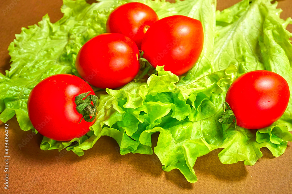 Red cherry tomatoes lie on a lettuce leaf. Red cherry tomatoes lie on a lettuce leaf.