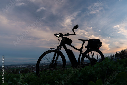 Black and gray electric bicycle in sunset time with cloudy sky