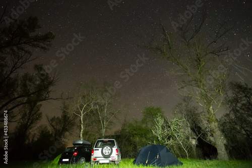 car touristic camp in night forest under a starry sky, night travel background
