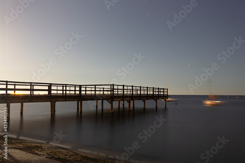 Wooden jetty over the sea with silk effect on a starry summer night, Spain