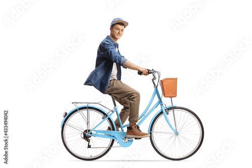Full length profile shot of a casual young male riding a city bicycle and looking at camera