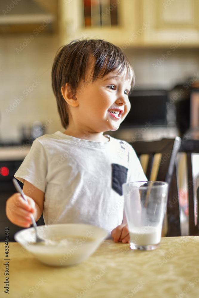 little boy eats breakfast, eats porridge and drinks milk little boy eats breakfast, eats porridge and drinks milk