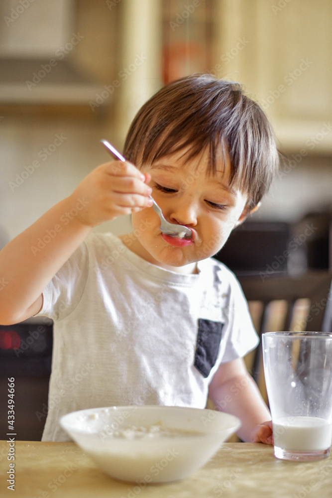 little boy eats breakfast, eats porridge and drinks milk little boy eats breakfast, eats porridge and drinks milk