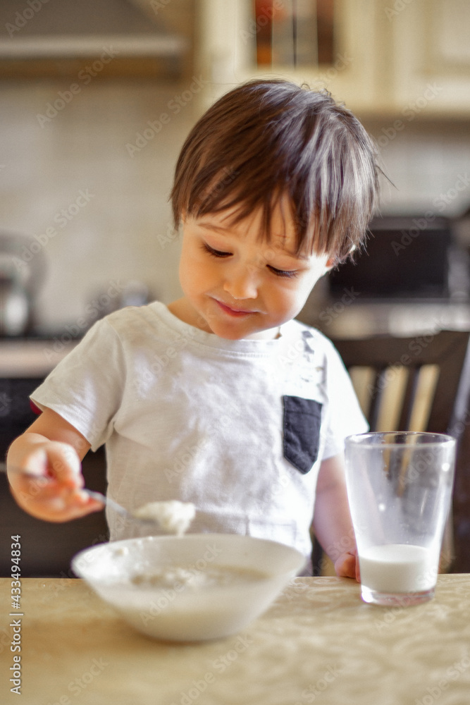 little boy eats breakfast, eats porridge and drinks milk little boy eats breakfast, eats porridge and drinks milk