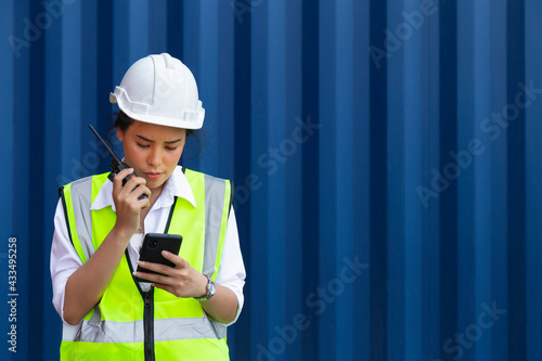 Asian confident woman engineer, technician or worker checking order and information from client on smartphone and report to coworker or manager. import, export, logistic and construction industrial.