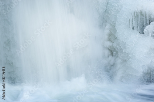 Winter landscape of a cascade captured with motion blur and framed by ice, Comstock Creek, Michigan, USA
