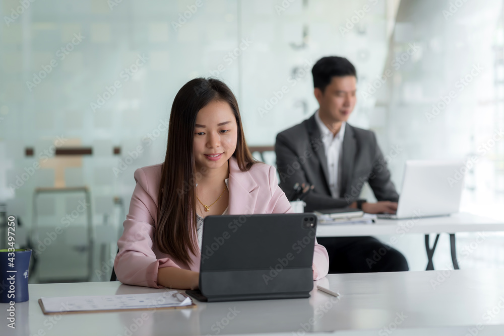 Front view of businesswoman using tablet notebook placed on the office table the back is blurry. Front view of businesswoman using tablet notebook placed on the office table the back is blurry.