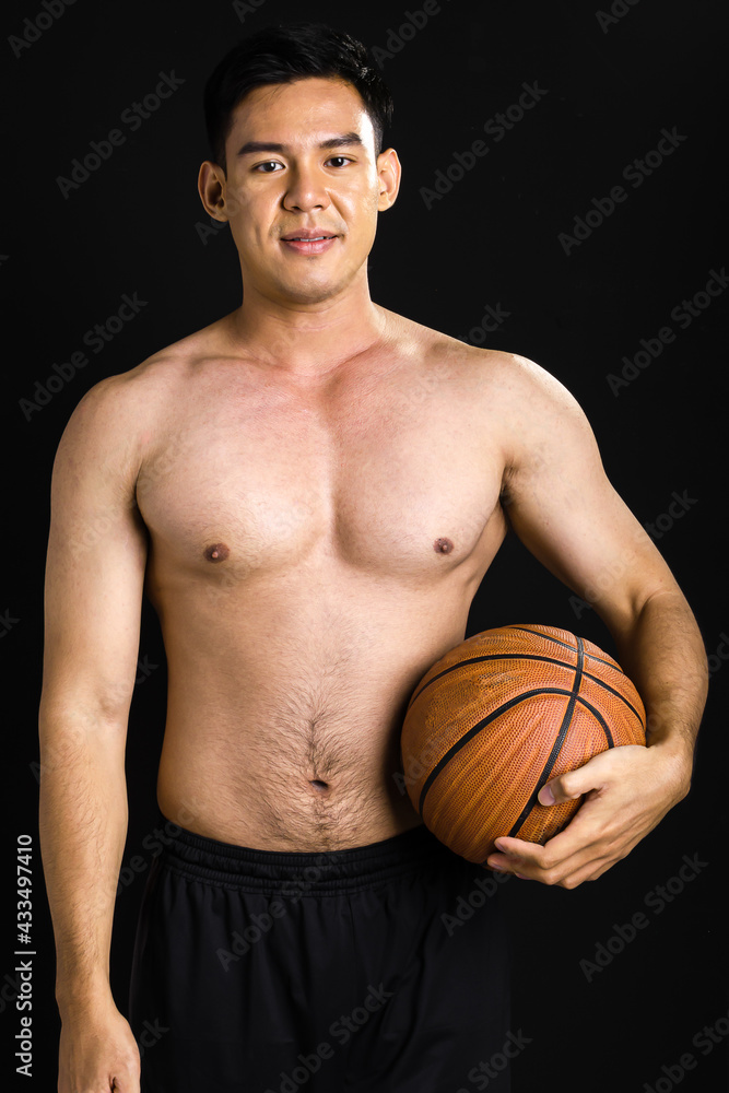 Asian strong healthy handsome muscular sportive man with shirtless, holding basketball, smiling with confidence, posing, looking at camera with confidence, standing on isolated black background.