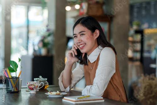 Asian businesswoman talking on the phone while having a coffee break at a café.