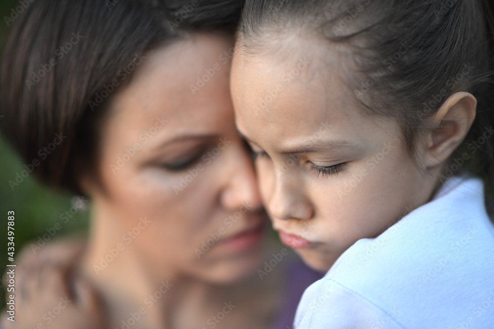 Close up portrait of sad woman and girl hugging Close up portrait of sad woman and girl hugging