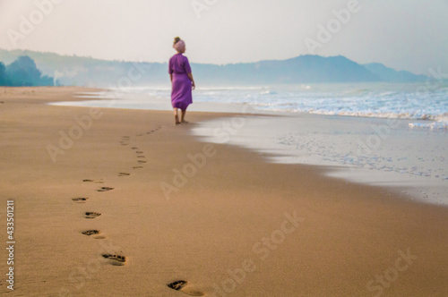 girl footprints in the sand ocean waves beach