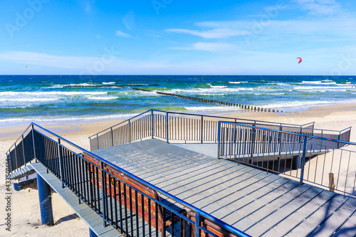 Entrance to beautiful beach in Grzybowo village near Kolobrzeg town and surfing kites on blue sky, Baltic Sea coast, Poland