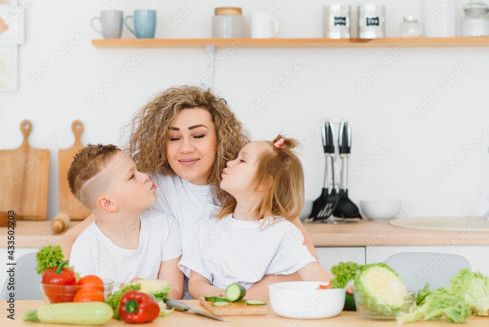 Family in a kitchen. Beautiful mother with children. Lady in white blouse. Family in a kitchen. Beautiful mother with children. Lady in white blouse.