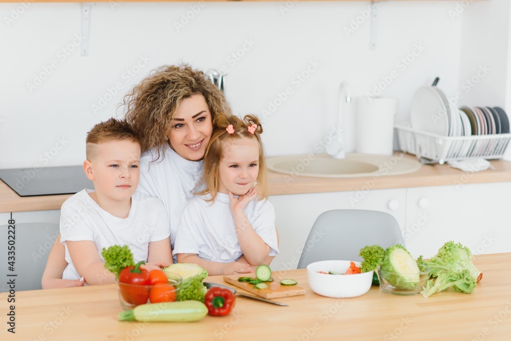 mother with children preparing vegetable salad at home