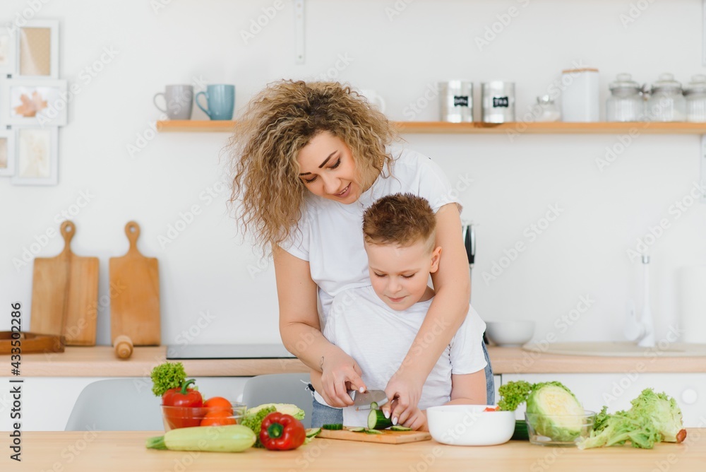 mother with children preparing vegetable salad at home