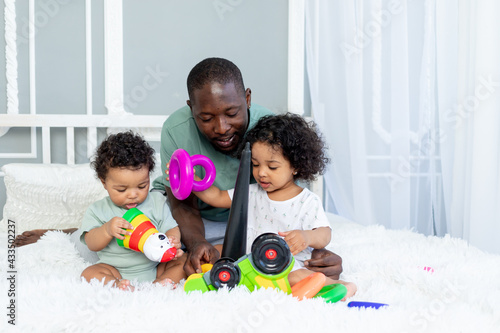 african-American family dad with kids babies play and collect a colorful pyramid at home on the bed  happy family