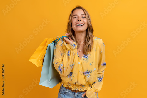 beautiful attractive smiling woman in yellow shirt and jeans holding shopping bags photo