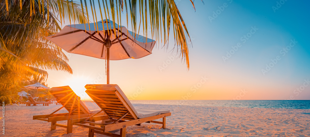 Tranquil tropical sunset scenery couple sun bed loungers, umbrella palm tree leaves. White sand sea view horizon, colorful twilight sky, calmness relaxation. Luxury vacation travel beach resort hotel
