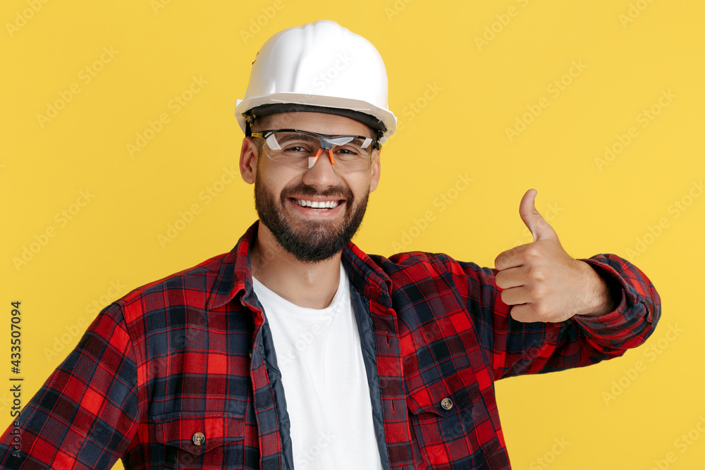 Cheerful bearded engineer or constructor man in casual outfit show good gesture over yellow background.