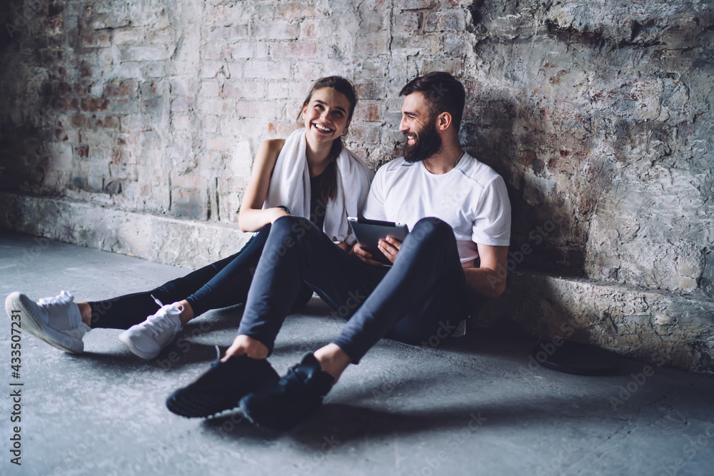 Laughing couple sitting on floor near brick wall