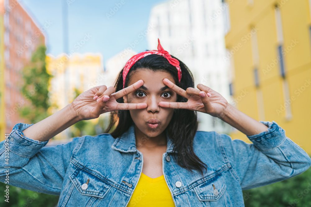 Portrait of cute dark skinned hipster girl having fun posing outdoors looking directly to the camera
