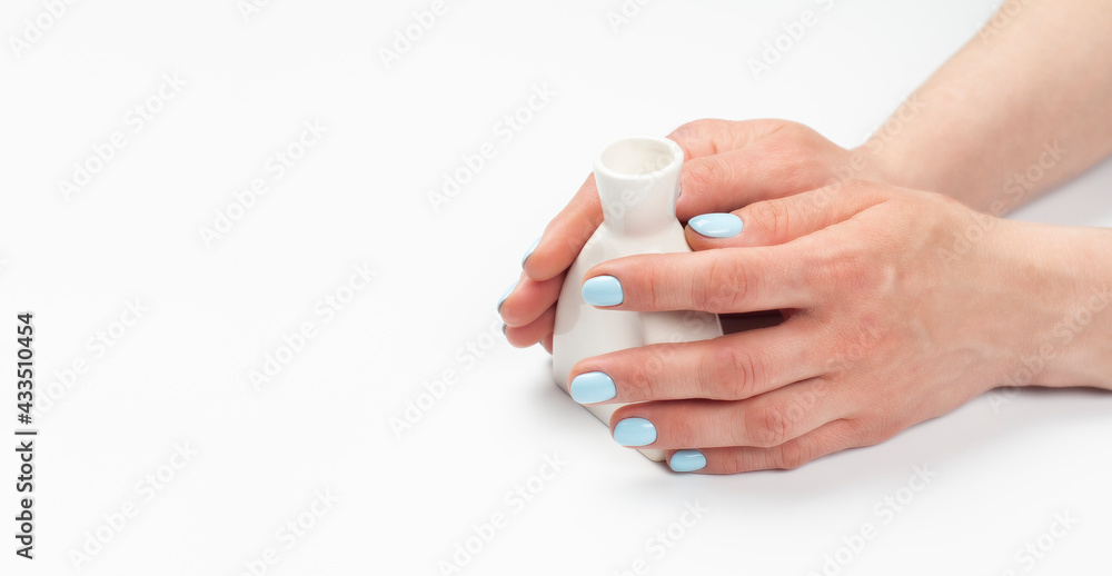 A vase in the hands of a woman with a turquoise manicure. Hands with manicure. On white background. Beautiful skin. A vase in the hands of a woman with a turquoise manicure. Hands with manicure. On white background. Beautiful skin.