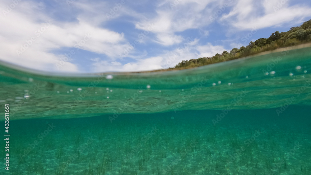 Split underwater photo of exotic Caribbean island seascape with emerald sea and beautiful clouds
