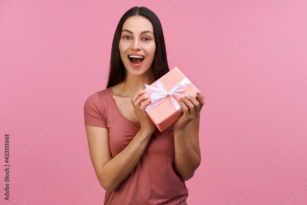 Studio shot of cute joyful brunette girl holding gift box with excited open mouth face expression Studio shot of cute joyful brunette girl holding gift box with excited open mouth face expression