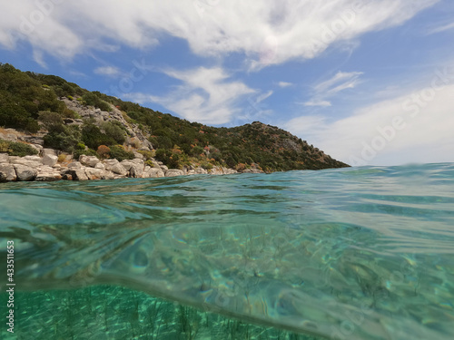 Split underwater photo of exotic Caribbean island seascape with emerald sea and beautiful clouds