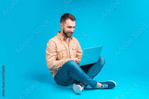 Portrait of handsome confident casually dressed bearded man sitting with his laptop computer and working on new project startup