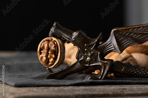 Dragon nutcracker is holding unshelled walnut on rustic napkin and wooden table photo