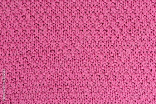 Pink knitted fabric pearl woolen background. The structure of the fabric with a natural texture. Fabric background. Knitted woolen background.
