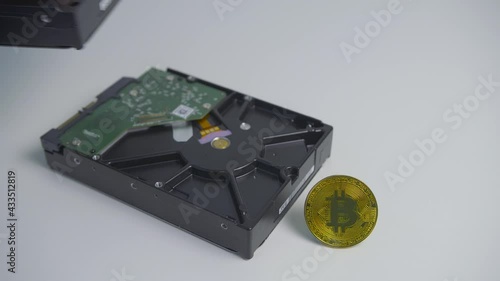 Male hand removing HDD disk drive from stack. Bitcoin coin standing on the white table. Cryptocurrency mining photo