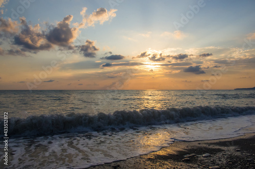 Amazing sea sunset on the pebble beach  the sun  waves  clouds