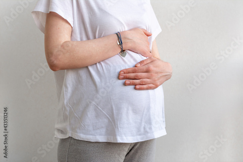 Pregnant woman holding hands on belly close up. Pregnancy concept.