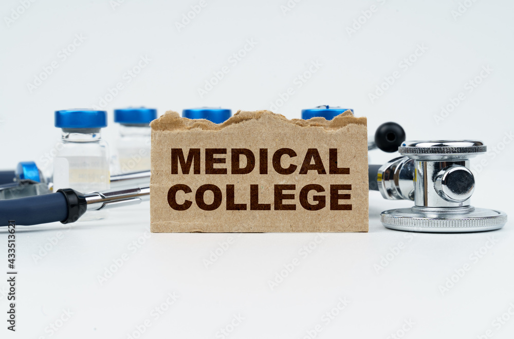 On a white table lie ampoules, a stethoscope and a cardboard with the inscription - MEDICAL COLLEGE