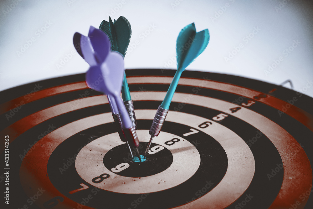 Close up shot of the dart arrow hit on bulleyes of dartboard to represent that the business reached the target of company with dark tone picture style. Target and goal as concept. Close up shot of the dart arrow hit on bulleyes of dartboard to represent that the business reached the target of company with dark tone picture style. Target and goal as concept.