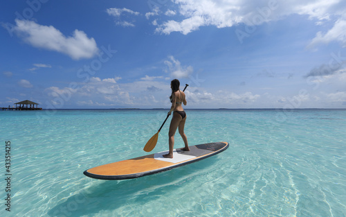 sports girl with paddle on surfboard in the Ocean  Maldives