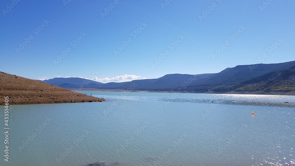 Obraz premium un bonito y tranquilo lago de montañas con agua azul limpia y cielo azul en España