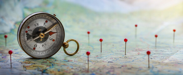 Magnetic compass  and location marking with a pin on routes on world map. Adventure, discovery, navigation, communication, logistics, geography, transport and travel theme concept background.. 
