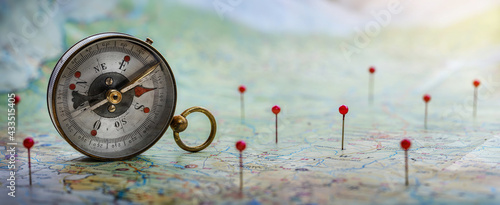 Magnetic compass and location marking with a pin on routes on world map. Adventure, discovery, navigation, communication, logistics, geography, transport and travel theme concept background.. 