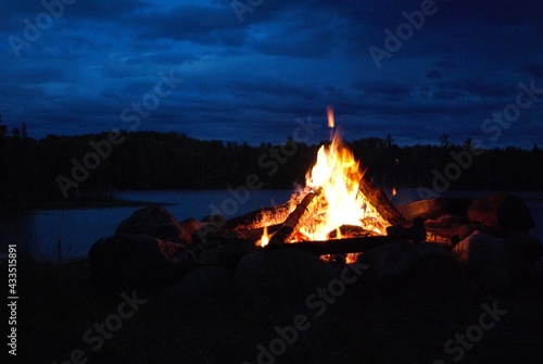 camp fire burning in a fire pit next to the lake