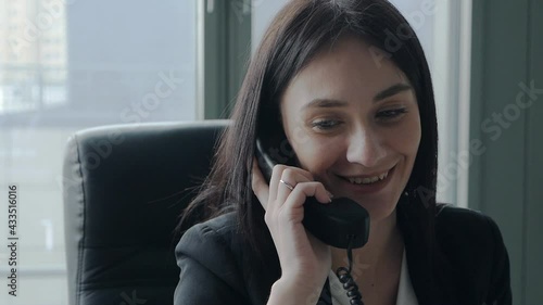 concept of business, technology, communication and people - young business woman smiling and talking on the phone in the office