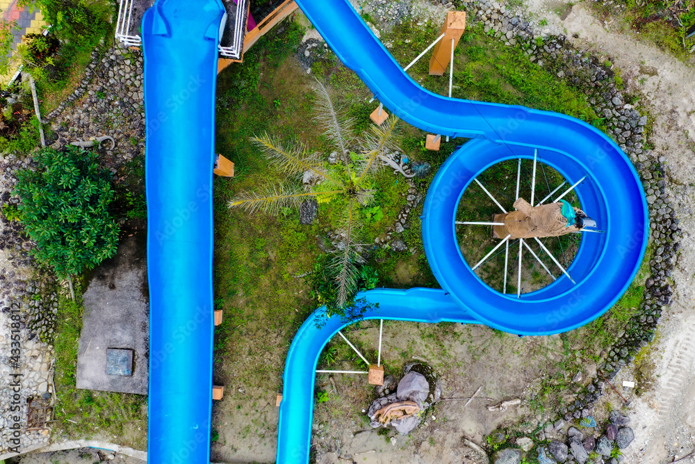 Aerial top view of two waterslides of which one goes straight and the second waterslide goes in circles