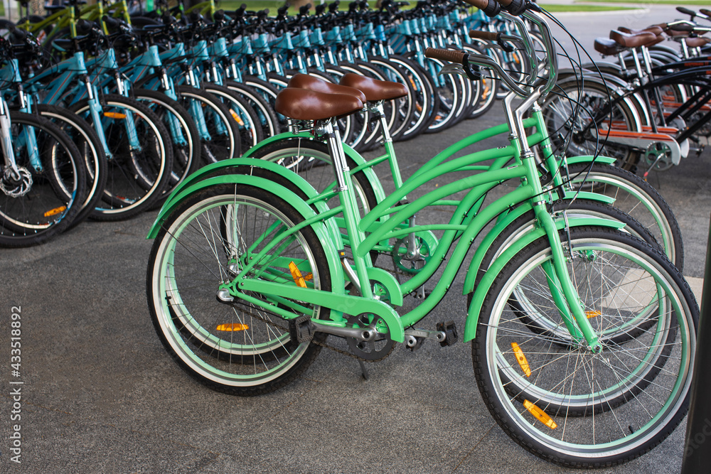 Bicycle rental in a public park, or store. Many bicycles are in a row, modern models in retro style, pastel green. Green transport concept, alternative view, environmental friendliness Bicycle rental in a public park, or store. Many bicycles are in a row, modern models in retro style, pastel green. Green transport concept, alternative view, environmental friendliness